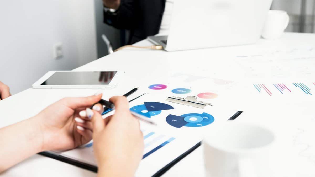 Team working on financial analysis with charts, data, and digital devices in an office setting.