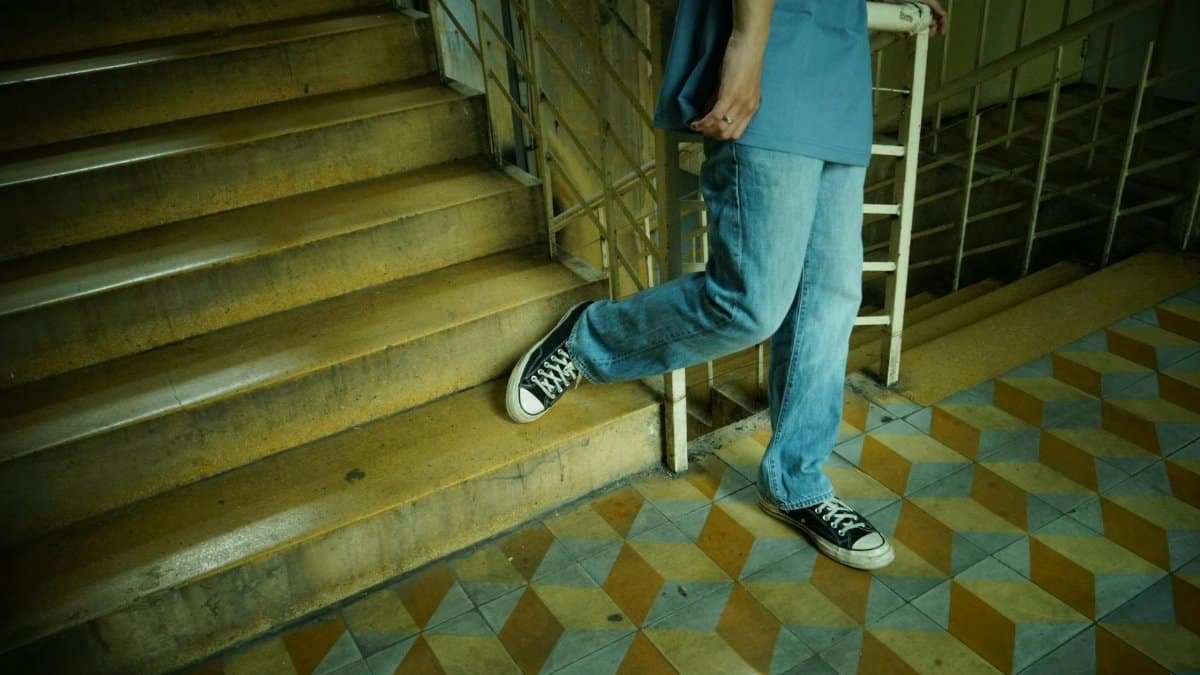 A person in casual clothing descends an indoor staircase, showcasing a relaxed, everyday lifestyle.