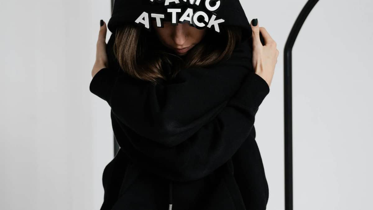 Woman in a black hoodie with 'panic attack' text, conveying emotions and mental health awareness.