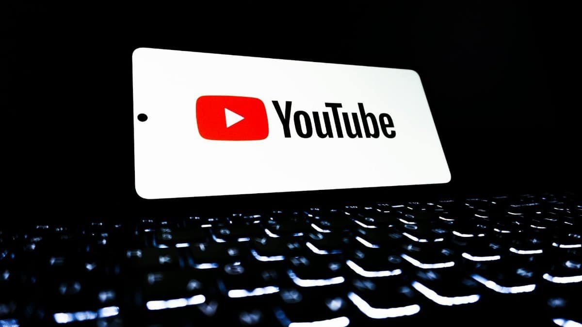 YouTube app icon displayed on a smartphone over an illuminated keyboard, representing digital media and online streaming.