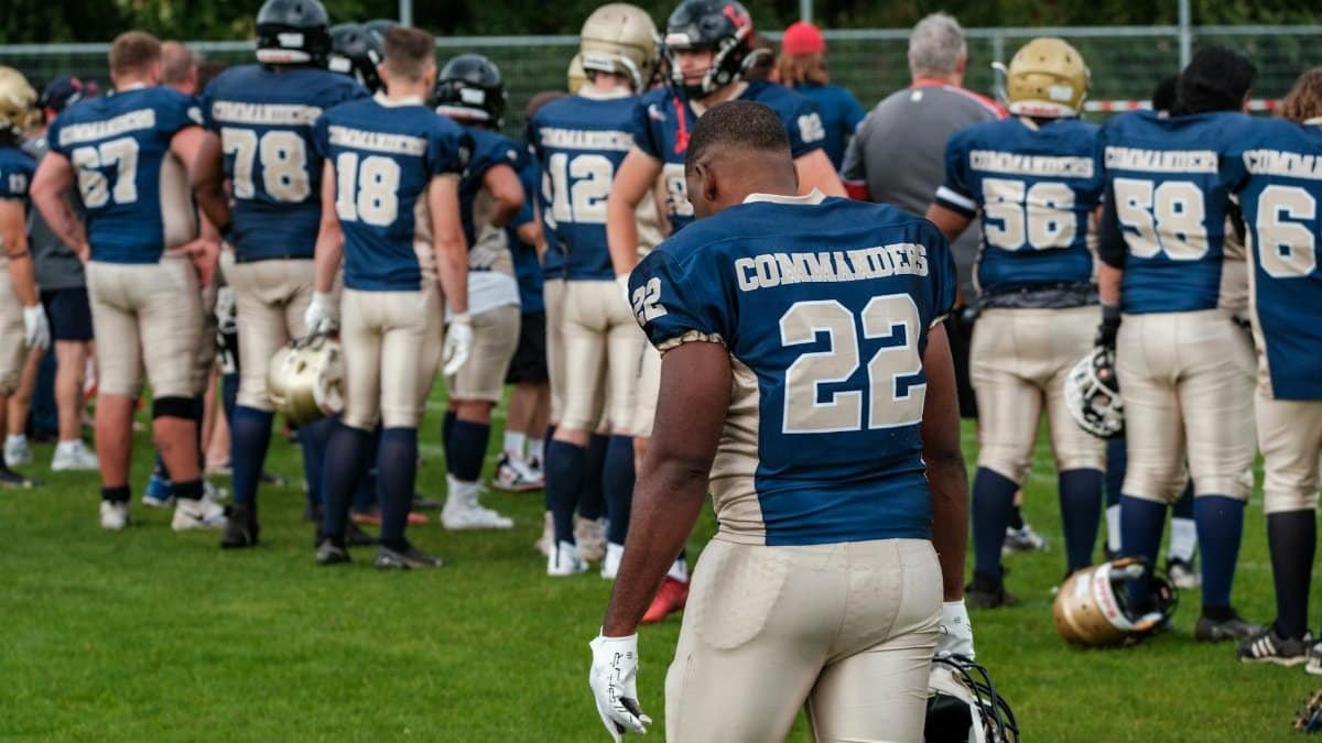 Football team players in helmets and uniforms preparing on the field.