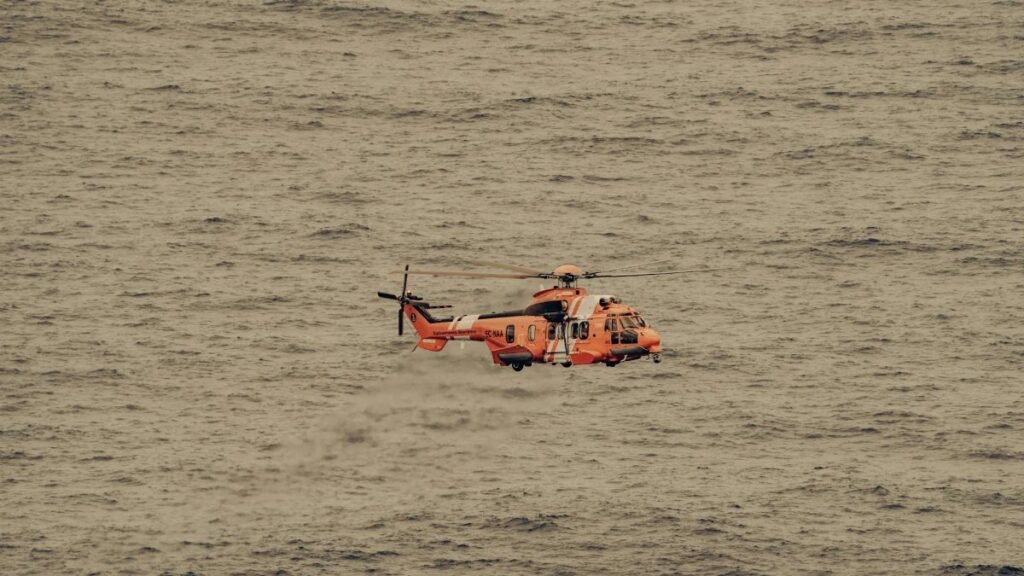 An aerial view of a rescue helicopter flying over the vast ocean, captured mid-flight.