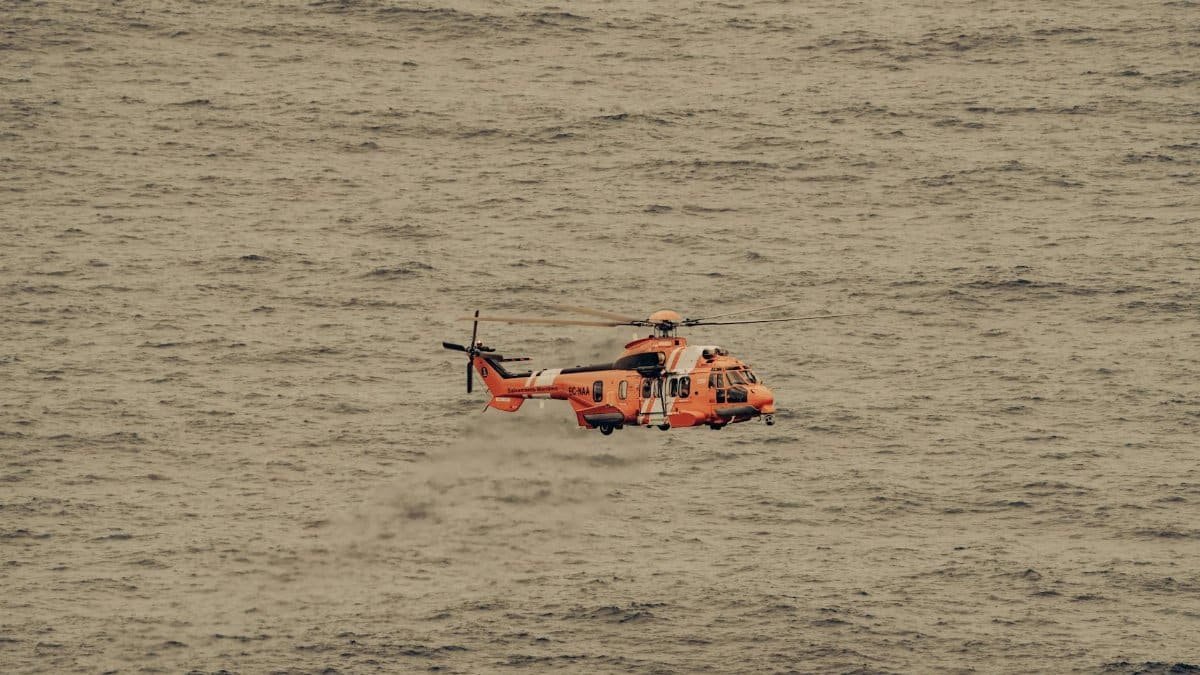 An aerial view of a rescue helicopter flying over the vast ocean, captured mid-flight.