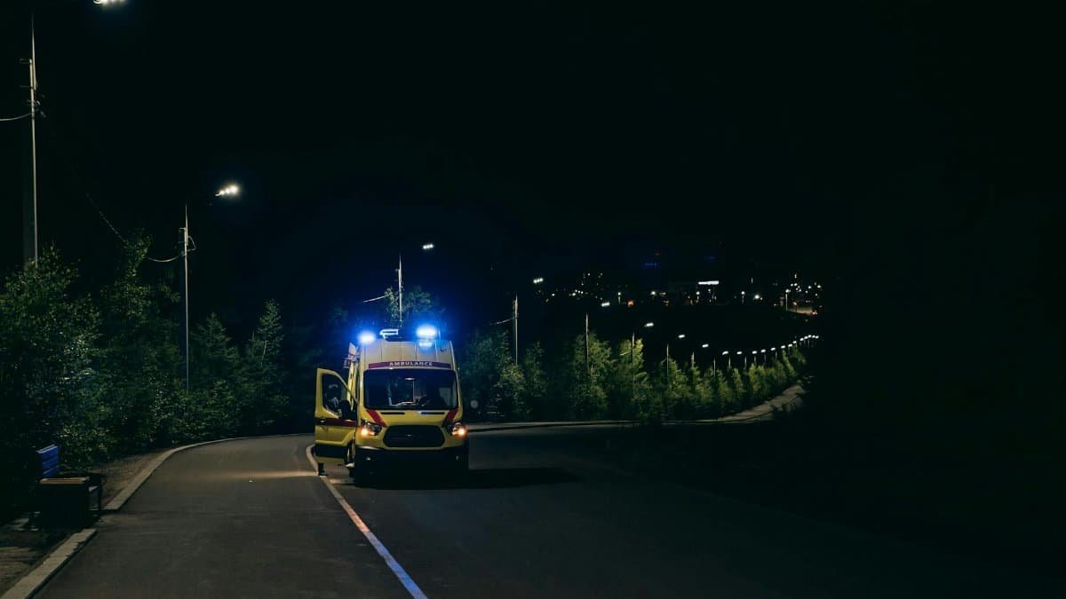 Ambulance with flashing lights on a rural road at night, ready for emergency response.