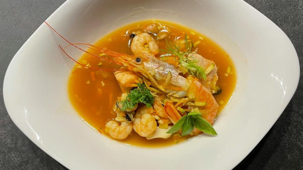 A vibrant seafood soup featuring fresh shrimps and fish in a rich broth.
