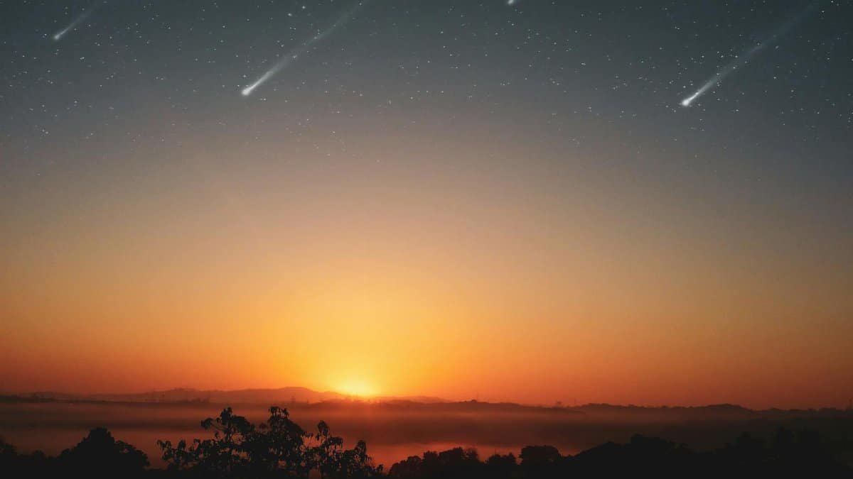 Experience the awe-inspiring beauty of a sunrise with shooting stars across a clear sky, perfect for serene landscapes.