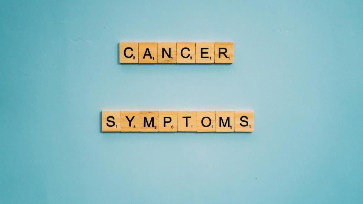 Scrabble tiles spelling 'Cancer Symptoms' on a light blue background, symbolizing awareness.
