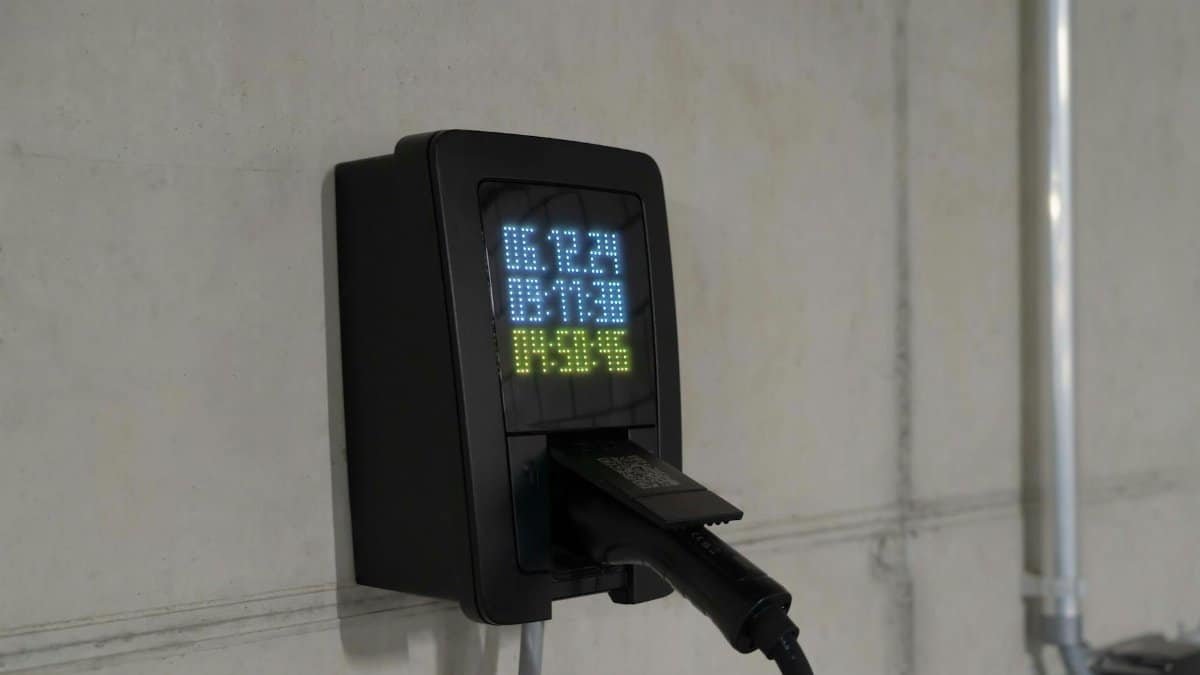 Close-up of an electric car charging station with digital display showing charge stats.