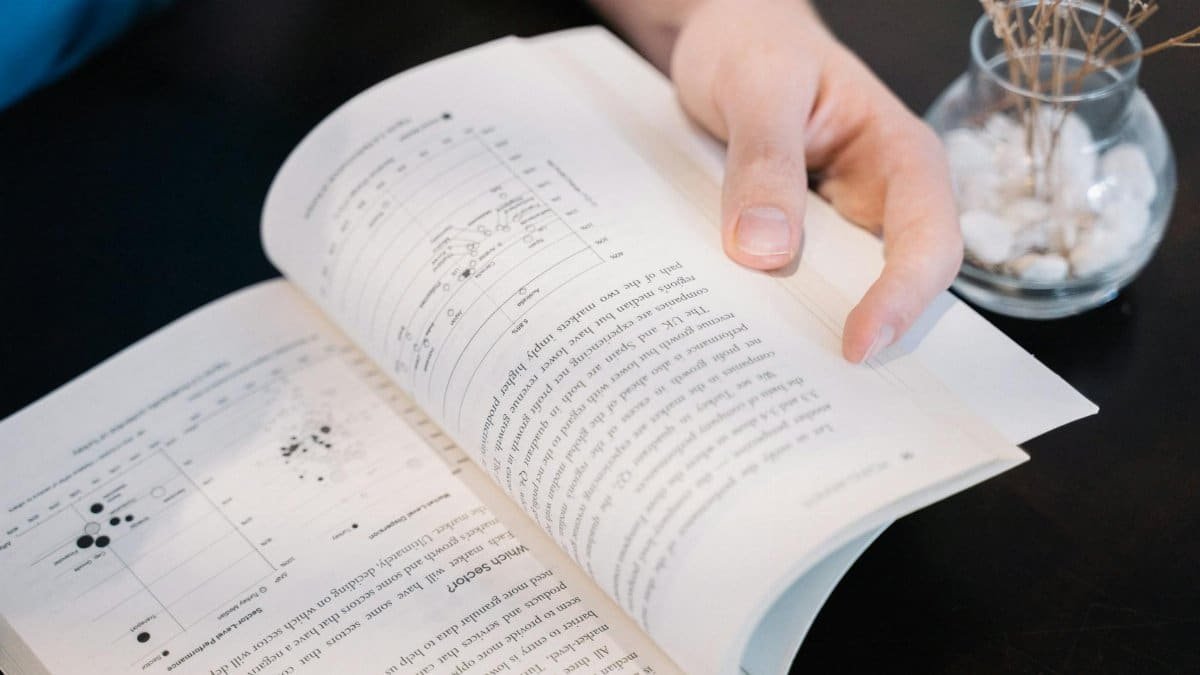 Close-up of a hand turning pages in a book with data charts and text.