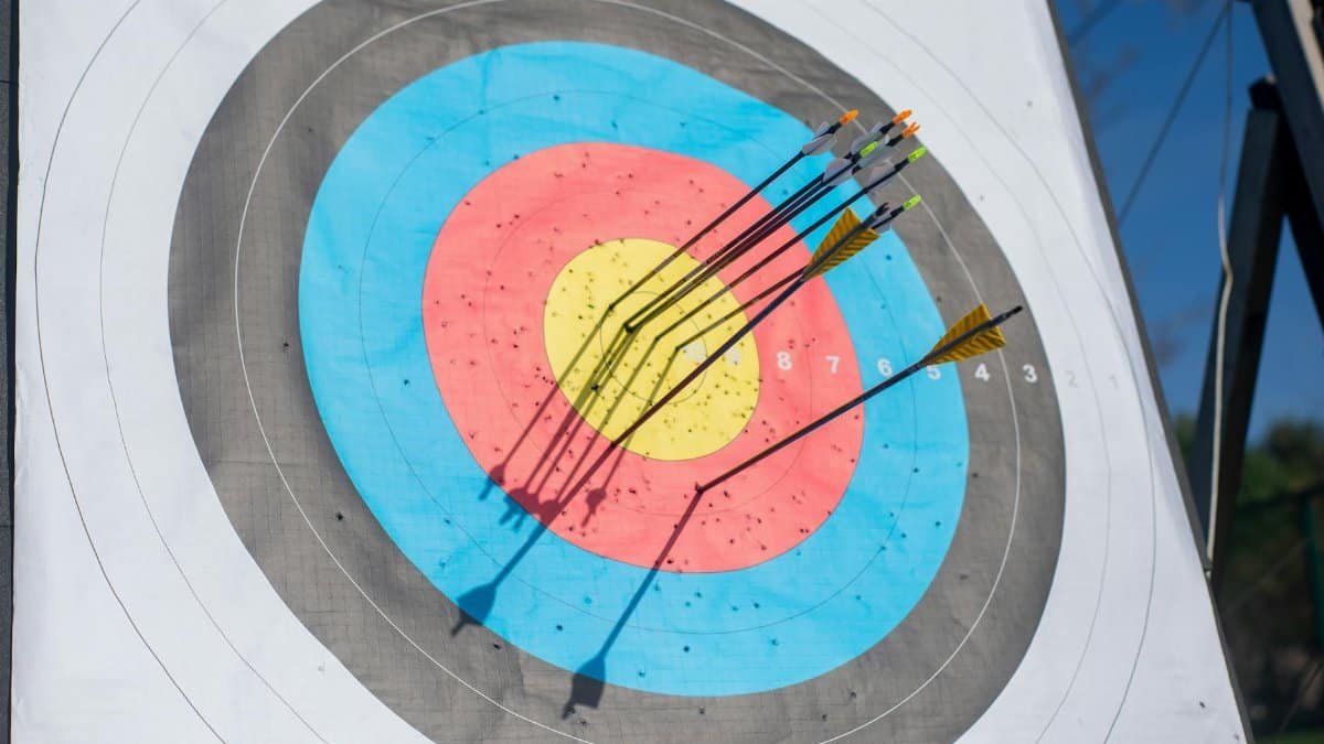 Close-up shot of an archery target hit by multiple arrows, achieving a perfect bullseye.