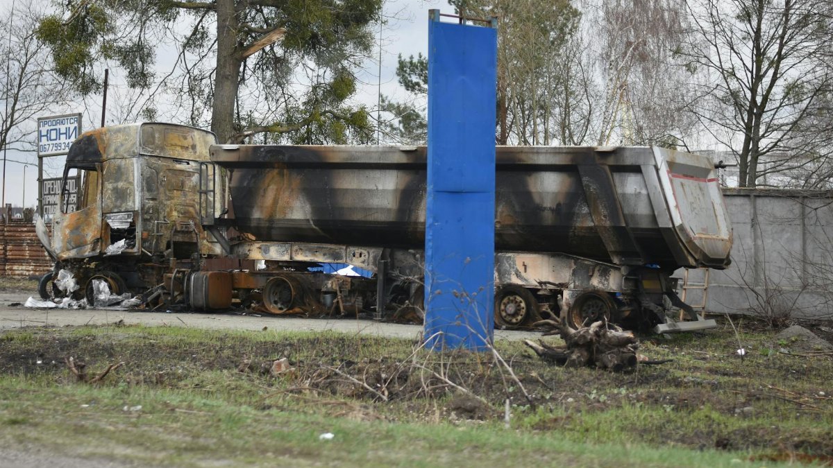 A heavily damaged and burnt truck left abandoned in a city street, creating a scene of destruction.