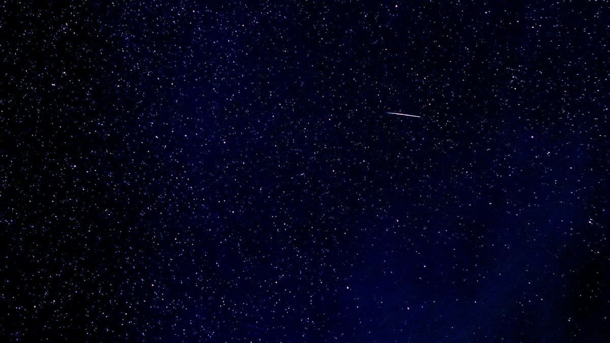 A breathtaking view of a starry night with a shooting star in East Tawas, Michigan, USA.