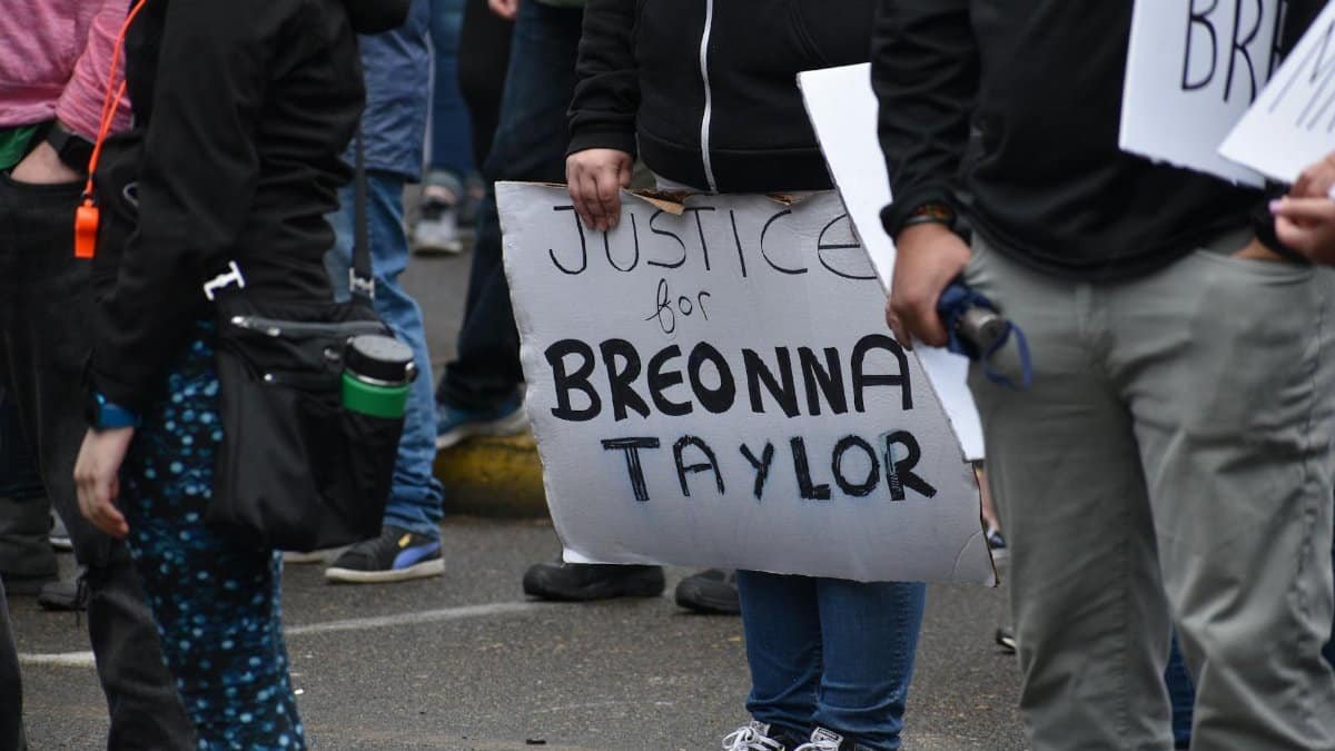 A peaceful protest advocating justice for Breonna Taylor with participants holding signs outdoors.
