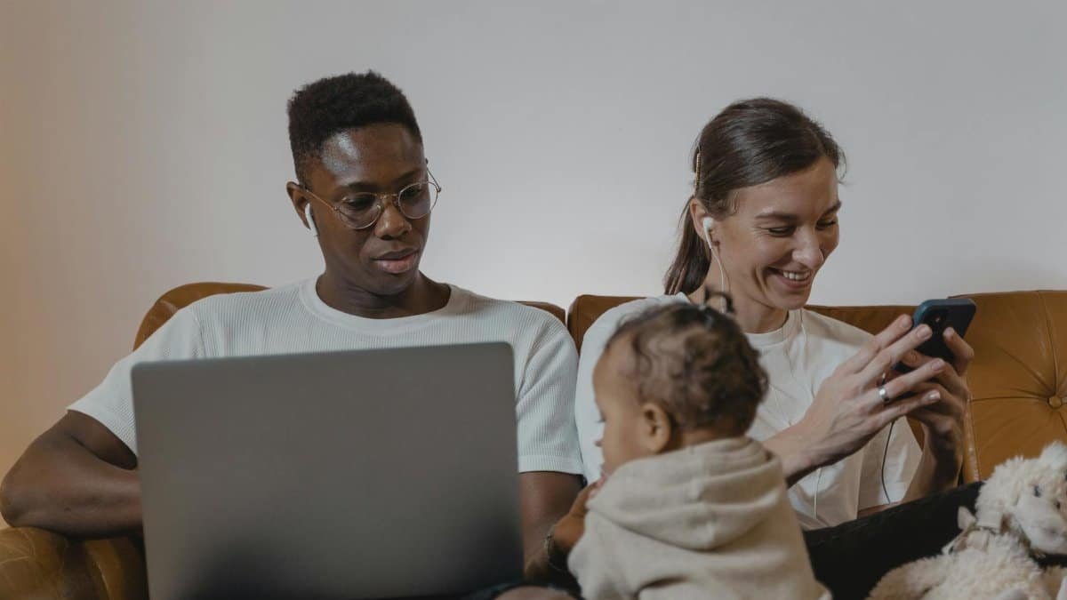 A family enjoying quality time together using tech devices like laptops and smartphones.