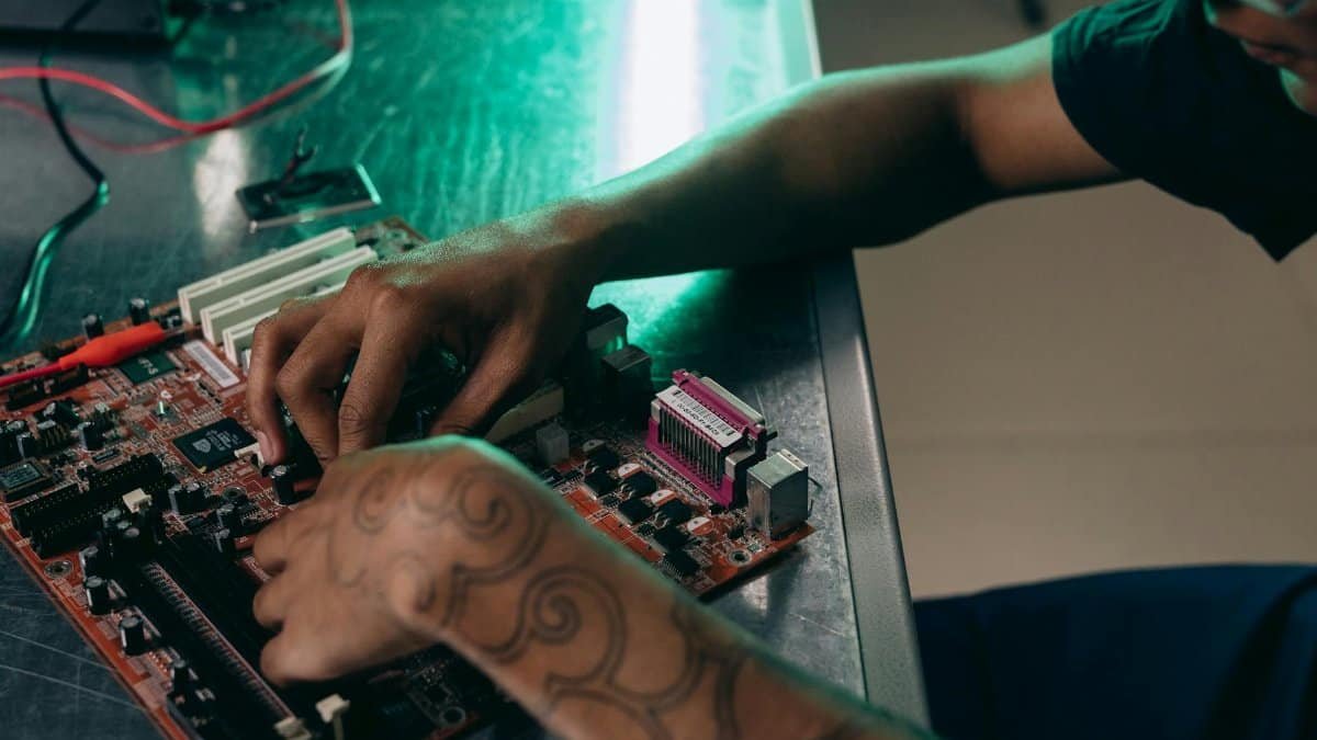 Close-up of person assembling a computer motherboard, showcasing a tattooed arm and tech innovation.