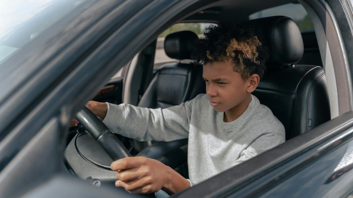 Teen boy learning to drive a car with focus and determination.