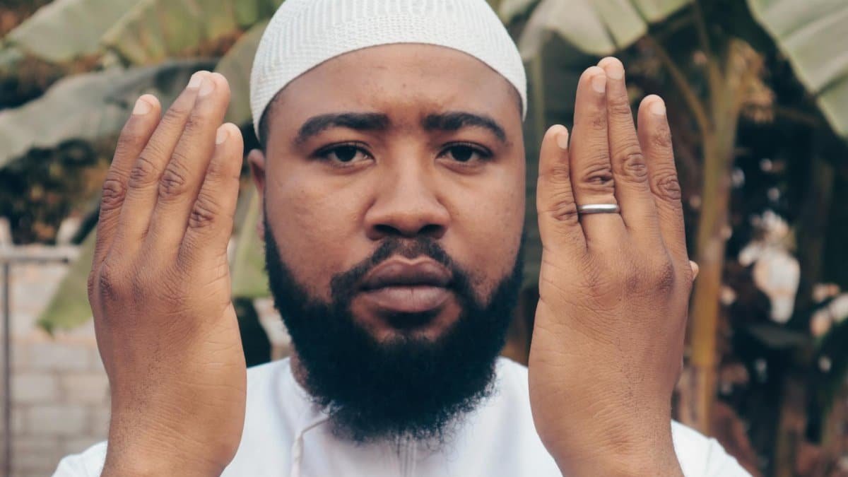 A young man in traditional clothing practices meditation outdoors with a focused expression.