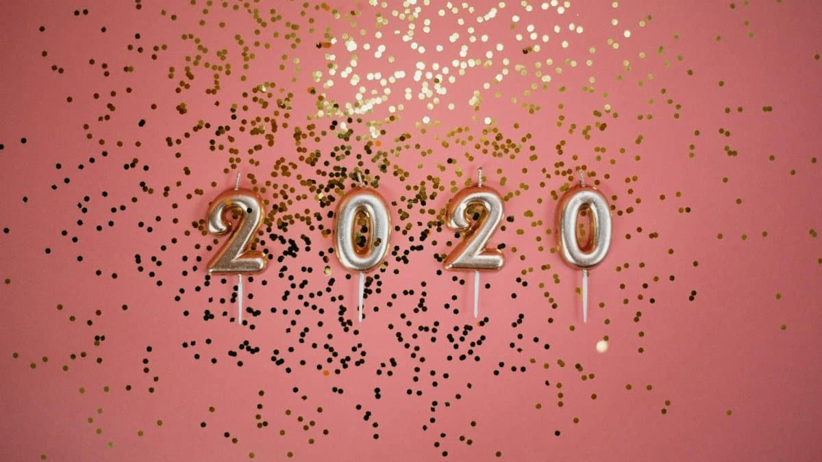 A festive pink background with 2020 candles and gold glitter, perfect for party themes.