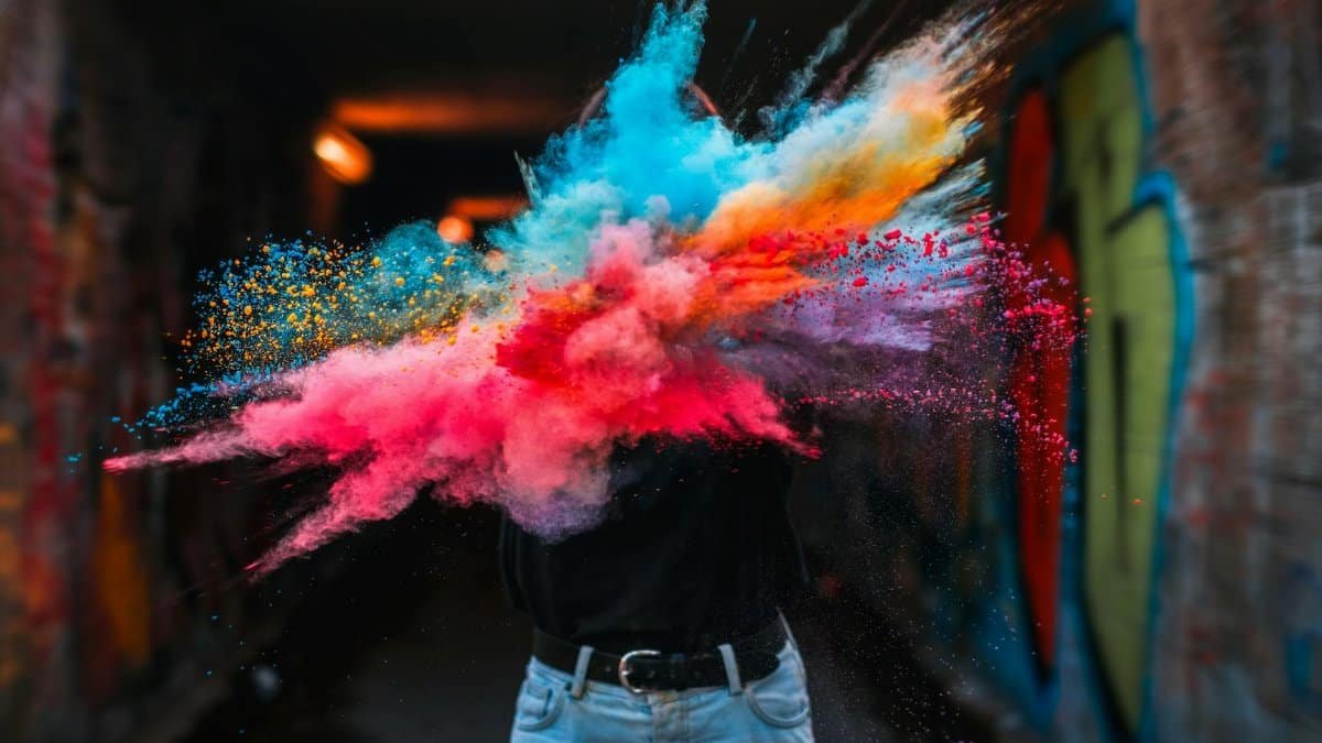 Vibrant powder explosion highlighting colorful creative expression with urban graffiti backdrop.