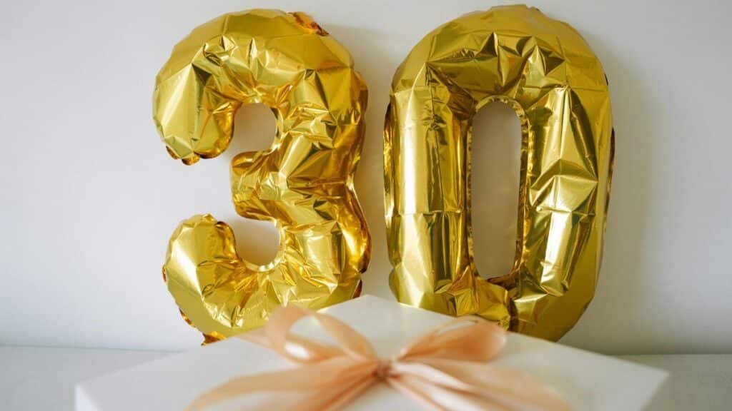 Golden 30 balloon with a wrapped gift box for a 30th celebration or birthday.