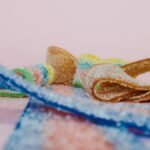 Vibrant macro shot of sugary sour candy ribbons on a pink background.