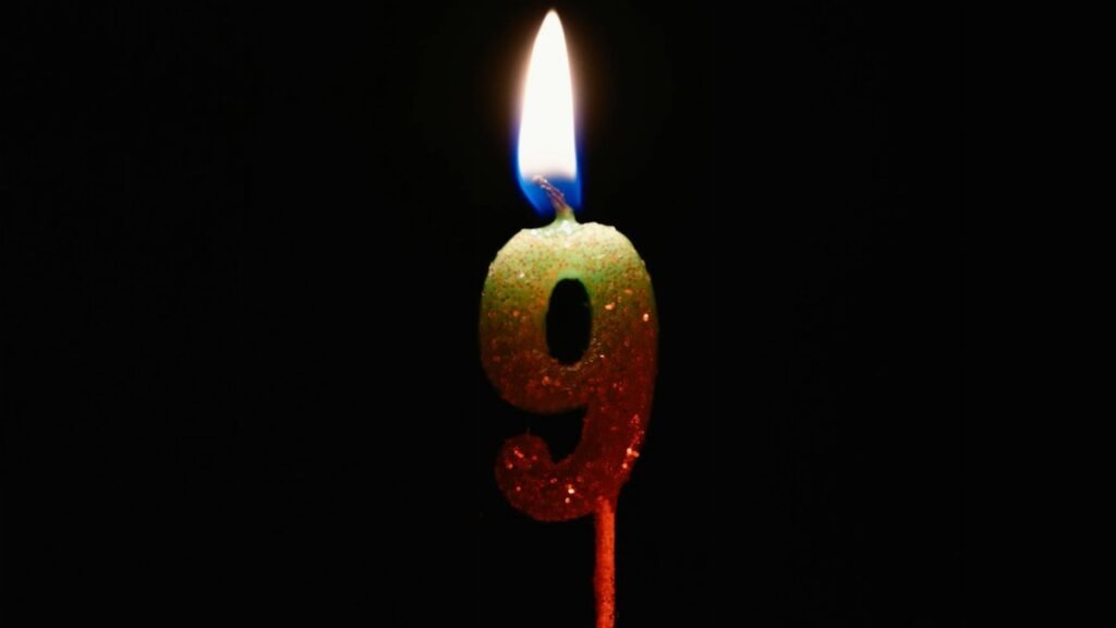 Burning number nine candle against a dark backdrop, perfect for birthdays or anniversaries.