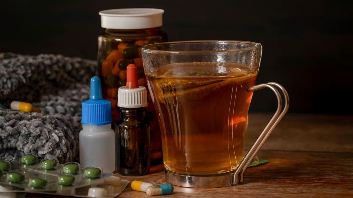 A cup of herbal tea with medications suggests natural cold remedies for healing.
