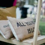 Outdoor cushions display with 'All You Need Is Love' slogan on burlap texture.