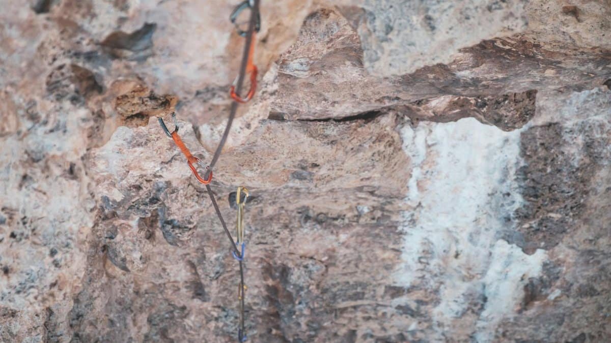 From above of stony uneven terrain with water flowing on rocks of cliff and safety rope in wild nature in daytime