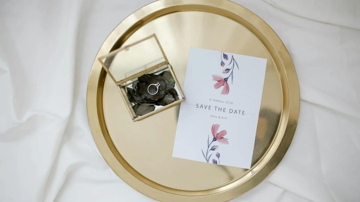 An elegant save the date card and engagement ring on a gold tray, perfect for weddings.