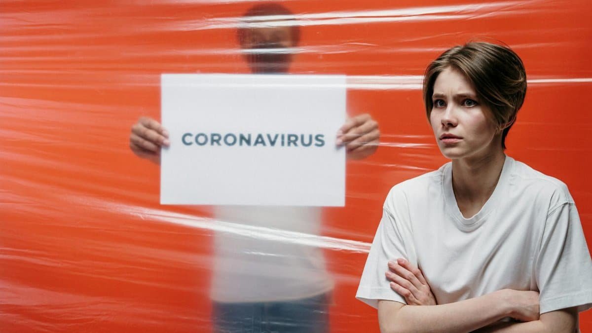 A worried person standing in front of a transparent barrier with 'Coronavirus' sign, illustrating pandemic anxiety.
