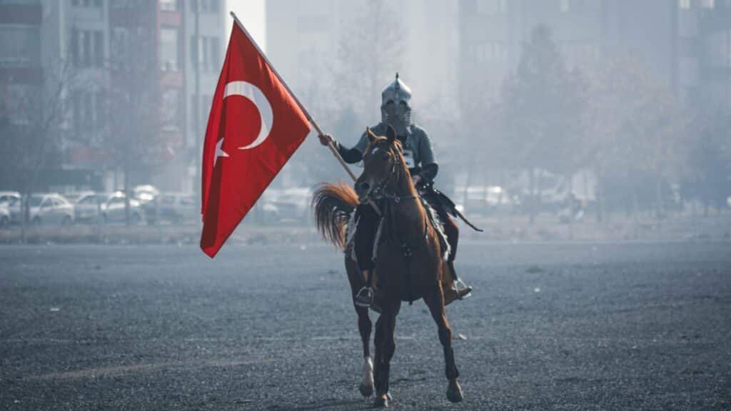 A historical reenactment of a Turkish horseman holding a flag in Konya, Türkiye.