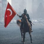 A historical reenactment of a Turkish horseman holding a flag in Konya, Türkiye.