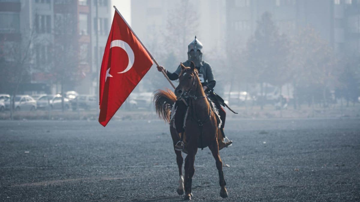 A historical reenactment of a Turkish horseman holding a flag in Konya, Türkiye.