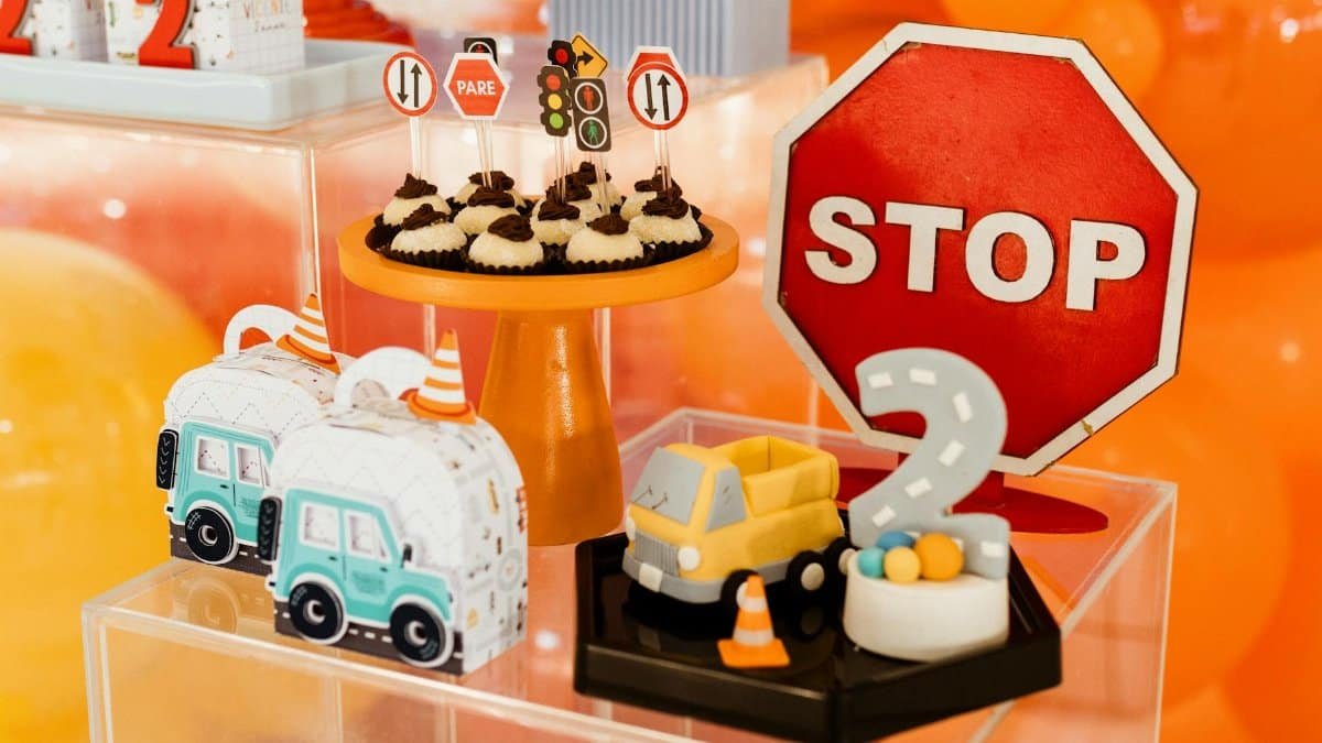 Vibrant traffic-themed birthday party setup with desserts and toy vehicles.