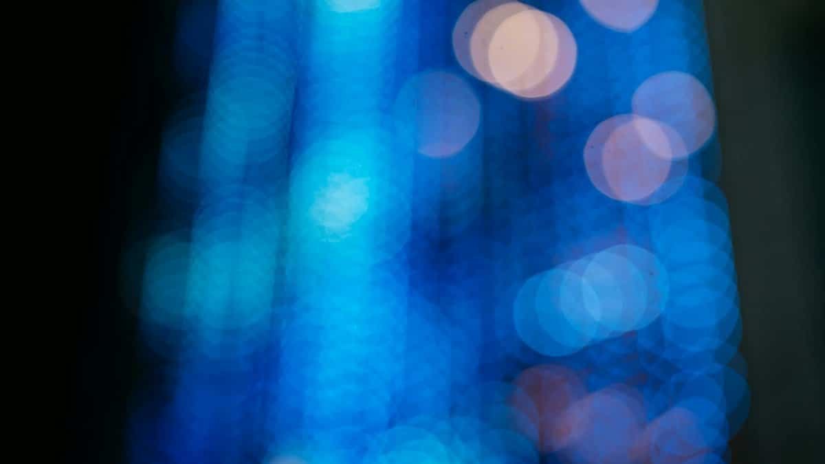 Abstract blue bokeh effect with circular shapes on a dark background, creating a dreamy atmosphere.