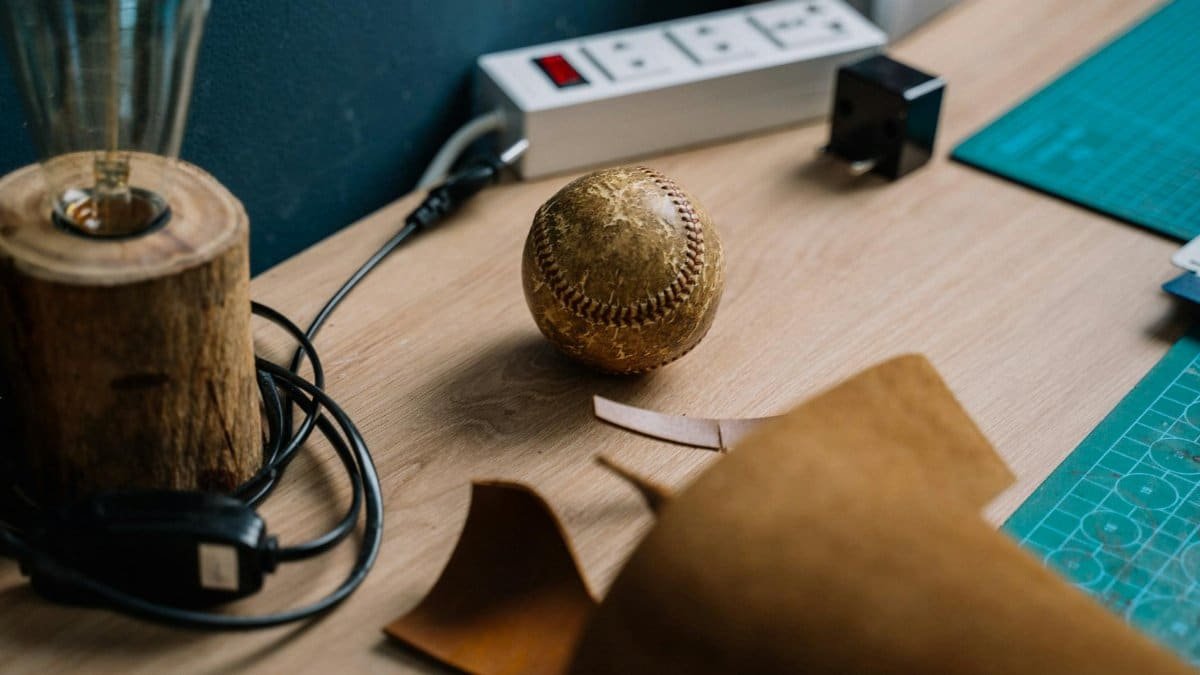 Close-up of a vintage baseball on a craft table with leather and tools.