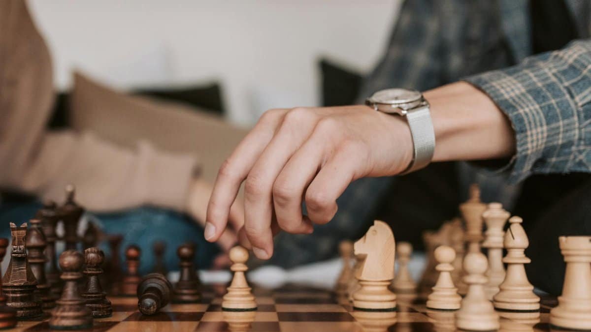 A person makes a strategic move in a chess game, highlighting the art of strategy.