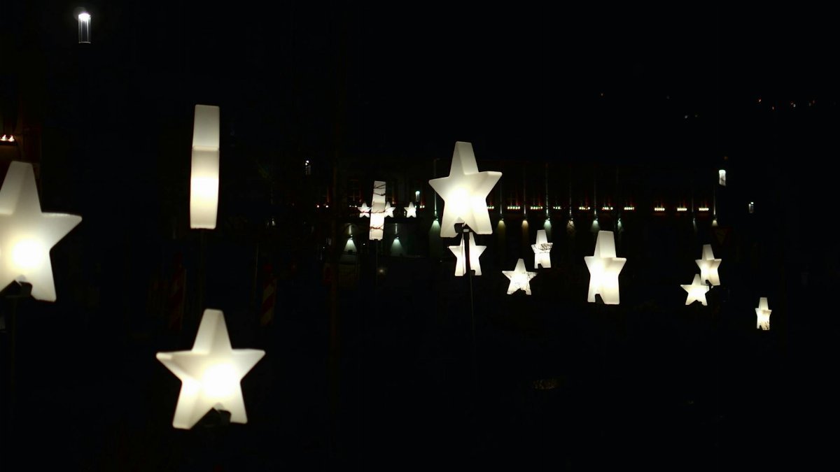 Creative star shaped garlands with glowing lamps decorating street against dark night sky