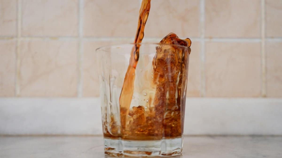Close-up of a refreshing dark beverage being poured into a clear glass, creating a splash.