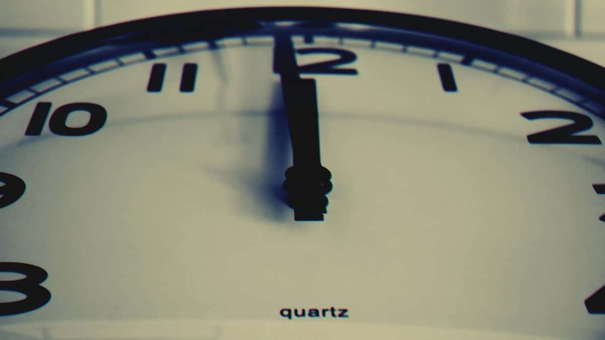 Detailed close-up shot of a wall clock showing the hour hand at midnight, highlighting time concept.