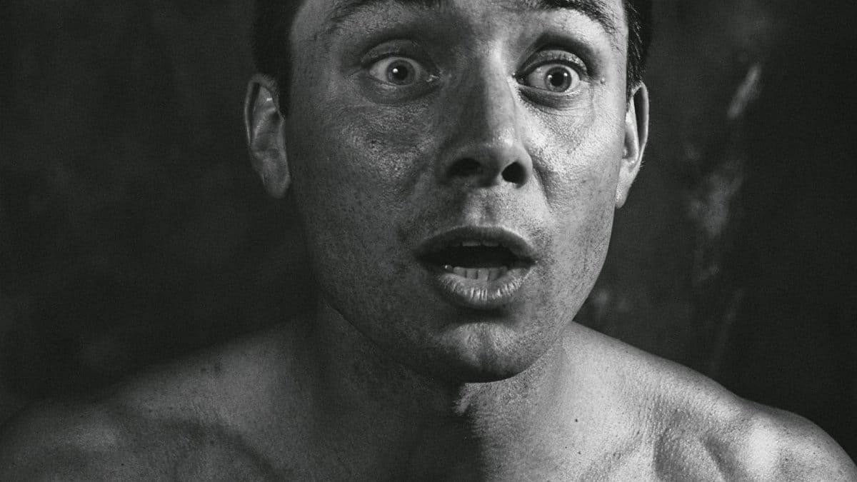 Close-up black and white portrait of a surprised man with a stunned expression.
