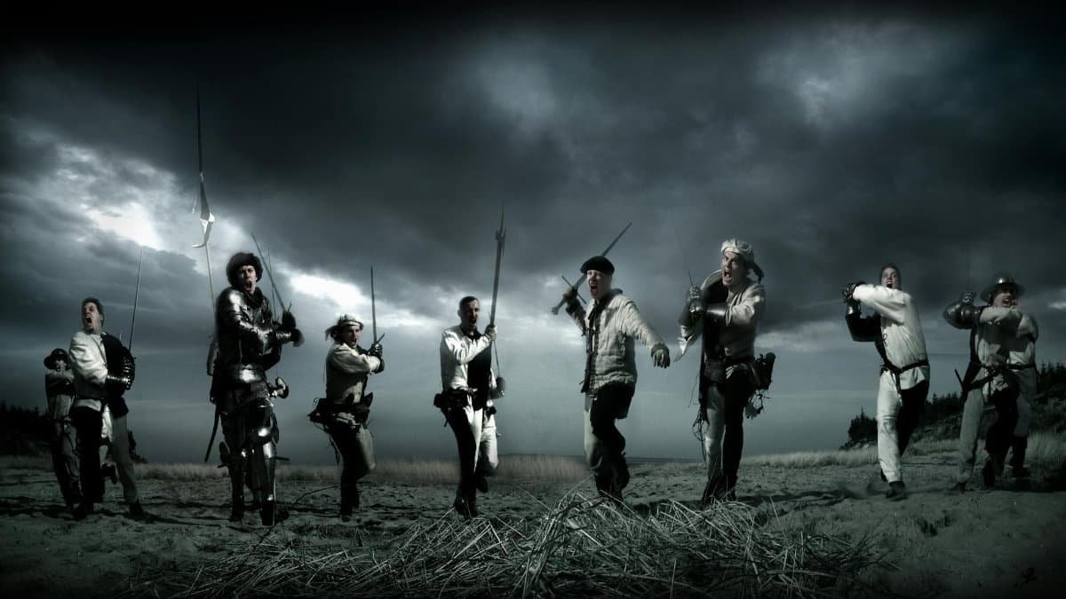 Dramatic scene of medieval knights charging in a reenactment battle under stormy skies.