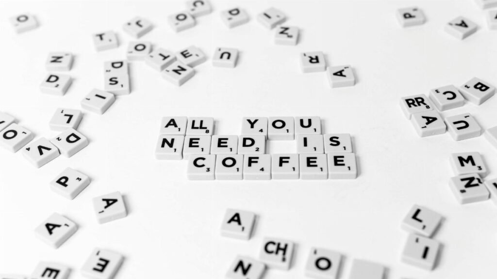 Scrabble tiles spell out 'All You Need Is Coffee' on a white background, offering a creative still life.