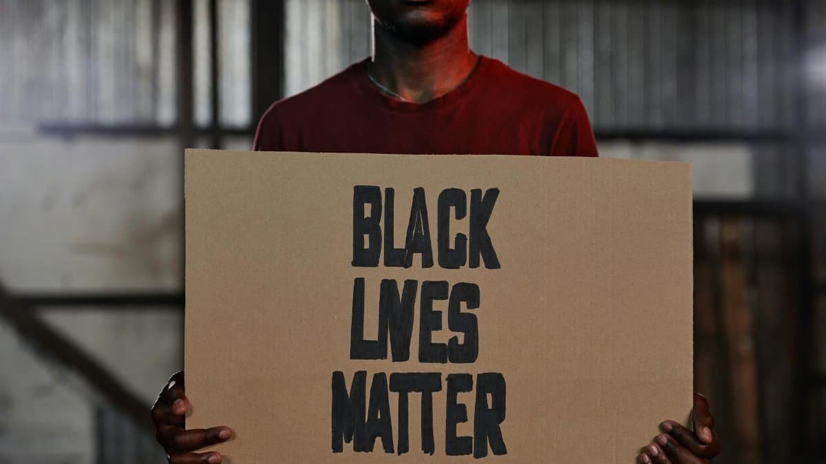 A person holding a Black Lives Matter sign during an indoor protest. Symbol of activism and social justice.