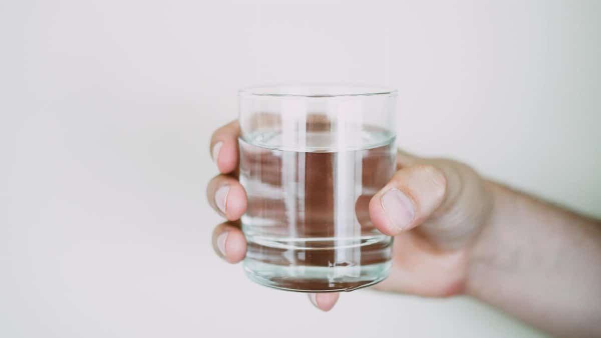A close-up shot of a hand holding a clear glass of water, symbolizing refreshment.