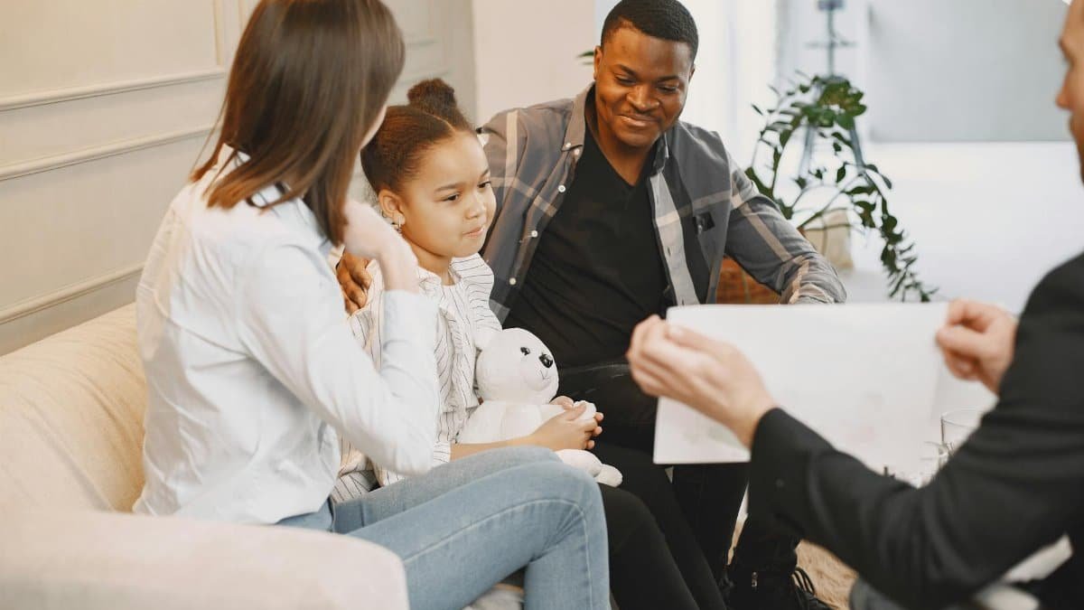A family therapy session with a young girl, parents, and therapist discussing together.