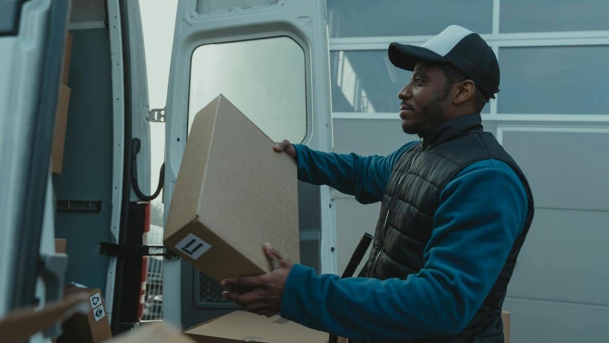Delivery man unloading parcels from van for shipment.