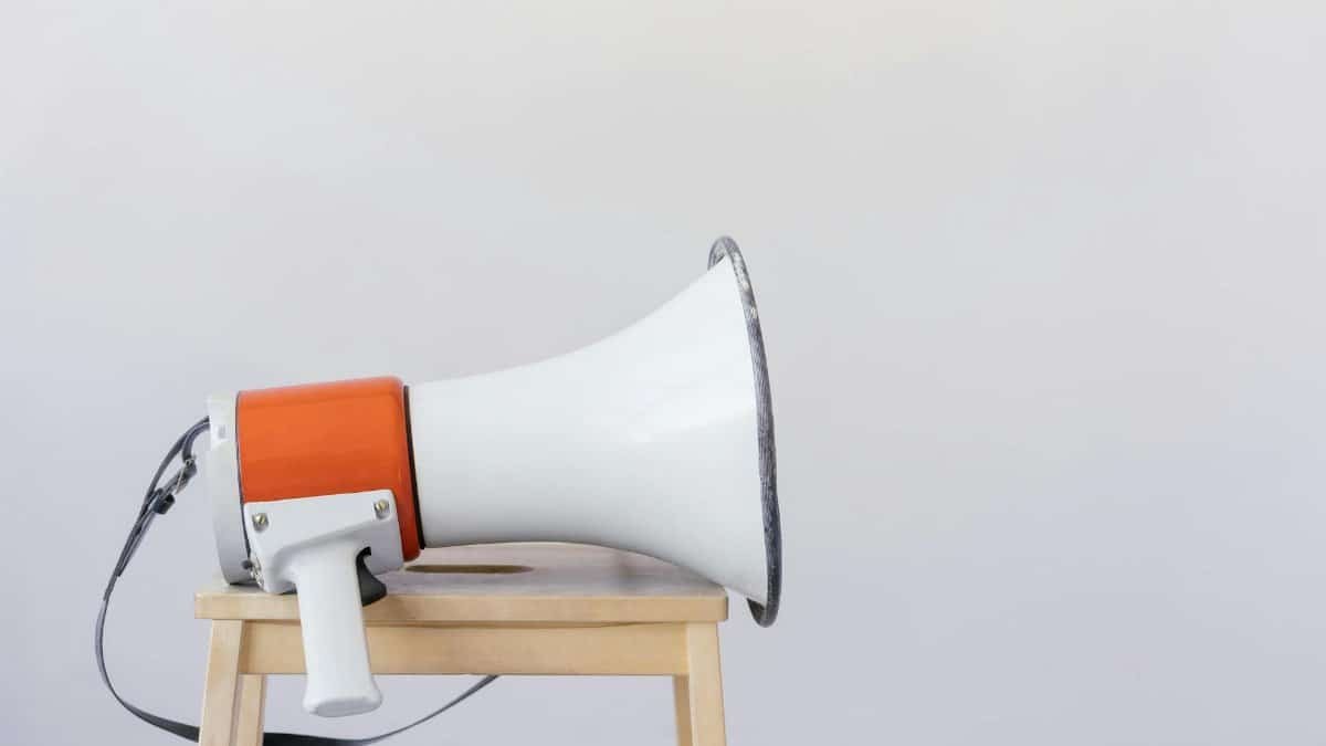 Close-up of a megaphone resting on a wooden chair with a minimalist background.