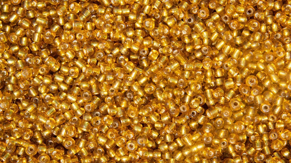 Close-up of vibrant gold beads creating a shimmering texture, ideal for backgrounds and crafts.